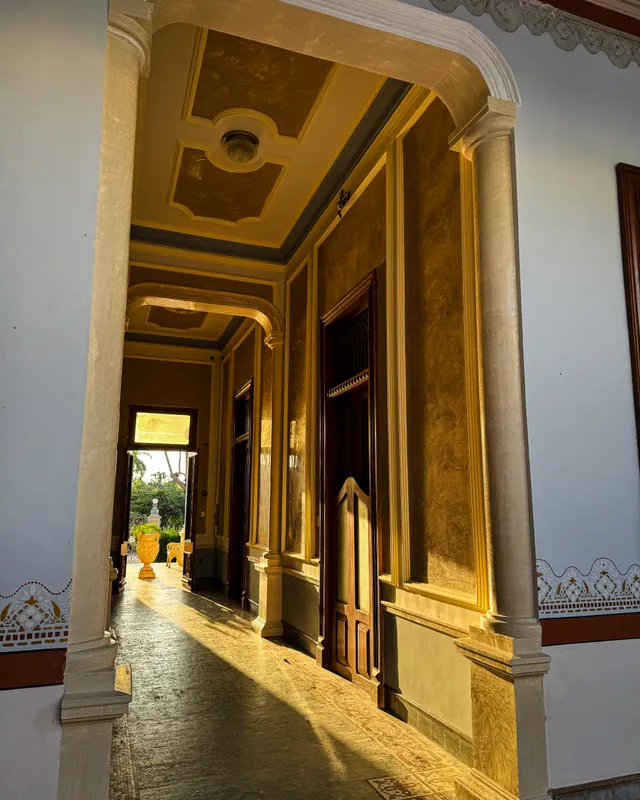 Corredor con columnas bañado por la luz dorada de la tarde, con vista al jardín