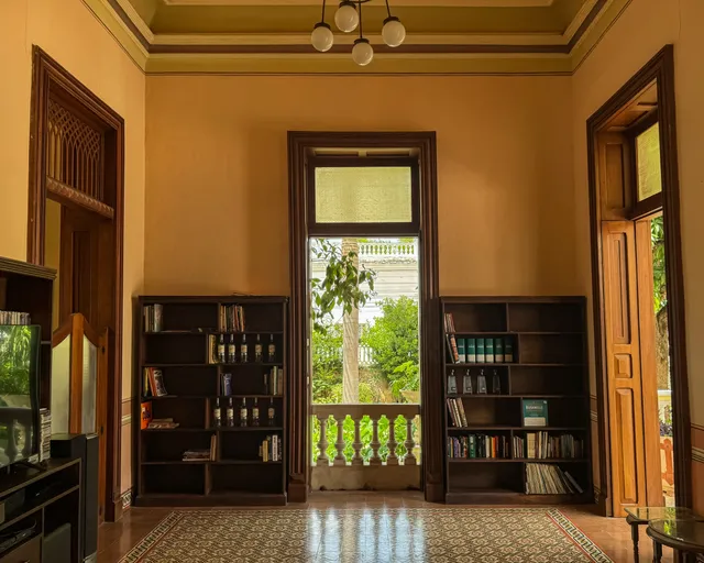 Biblioteca con dos libreros oscuros junto a una puerta al jardín y piso de pasta