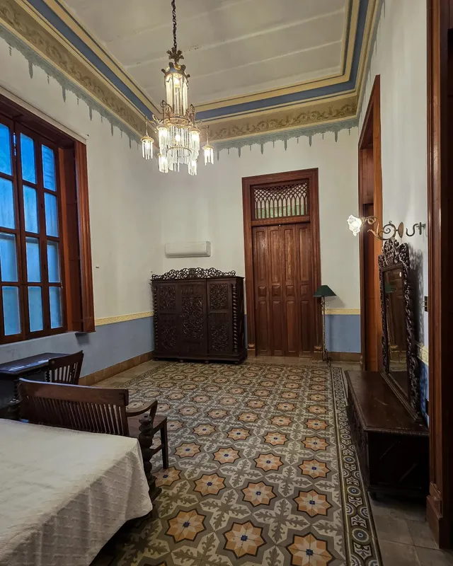 Habitación con candil, cómoda de madera tallada y piso de pasta con motivos de estrella