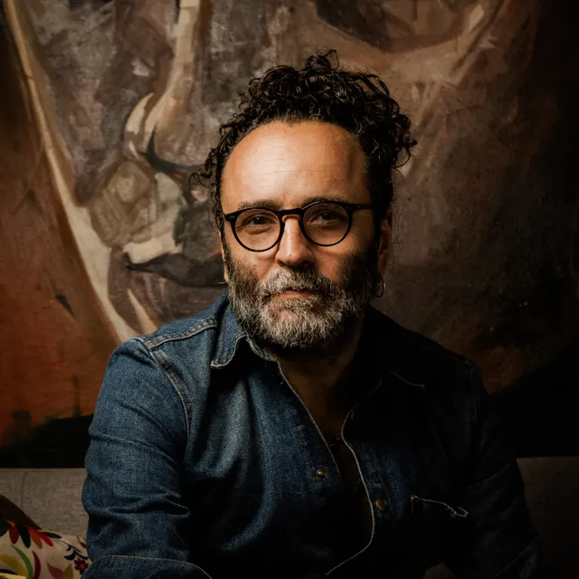 Retrato de Rodolfo Baeza frente a una de sus pinturas