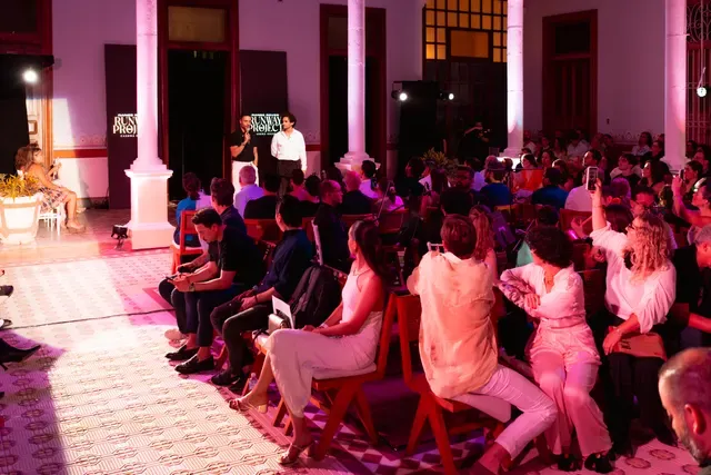 Invitados sentados en el corredor de Casona Cicero durante Runway Project, bajo iluminación rosa